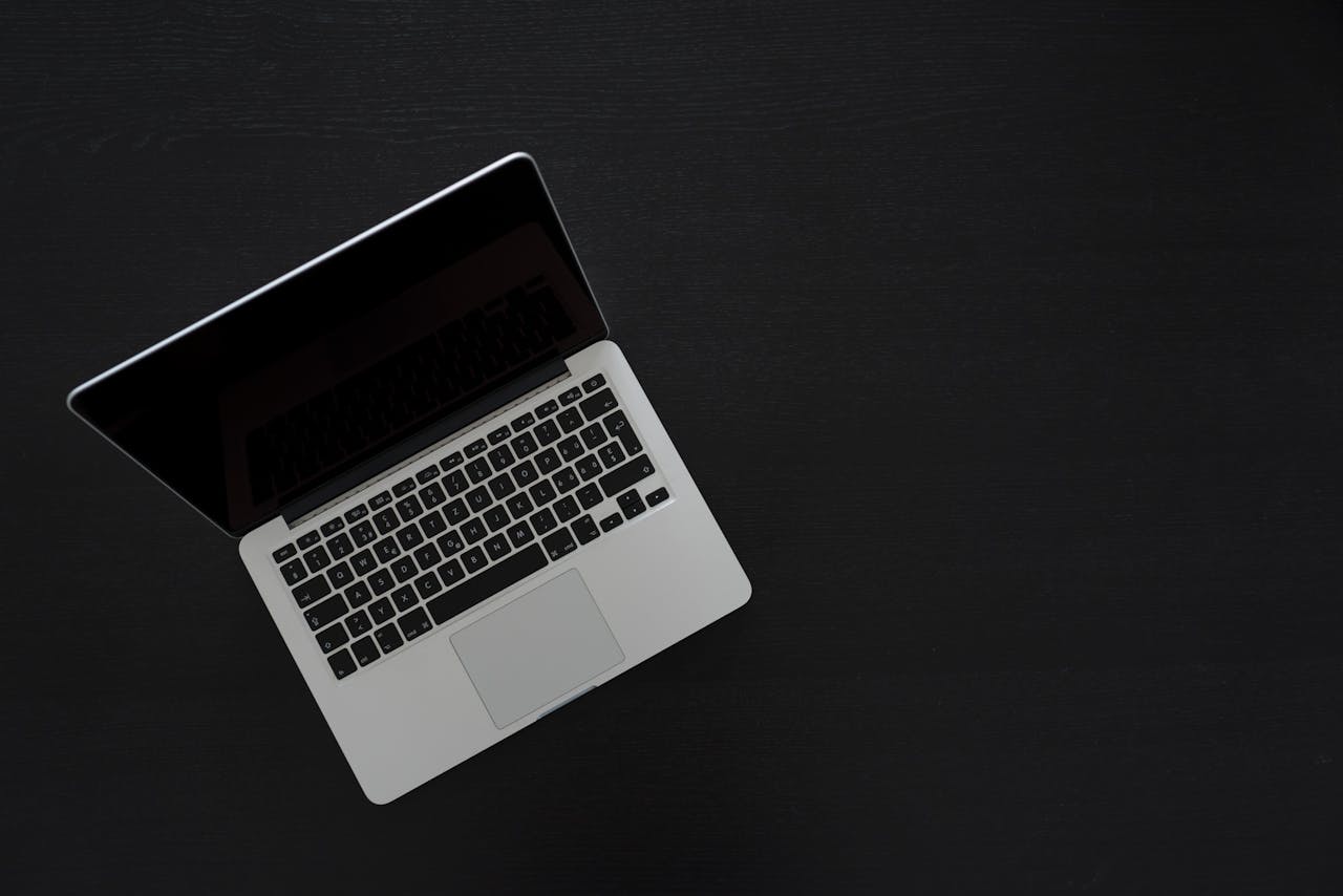 who-we-are-img Overhead view of a MacBook laptop on a dark desk, showcasing modern technology and minimalism.