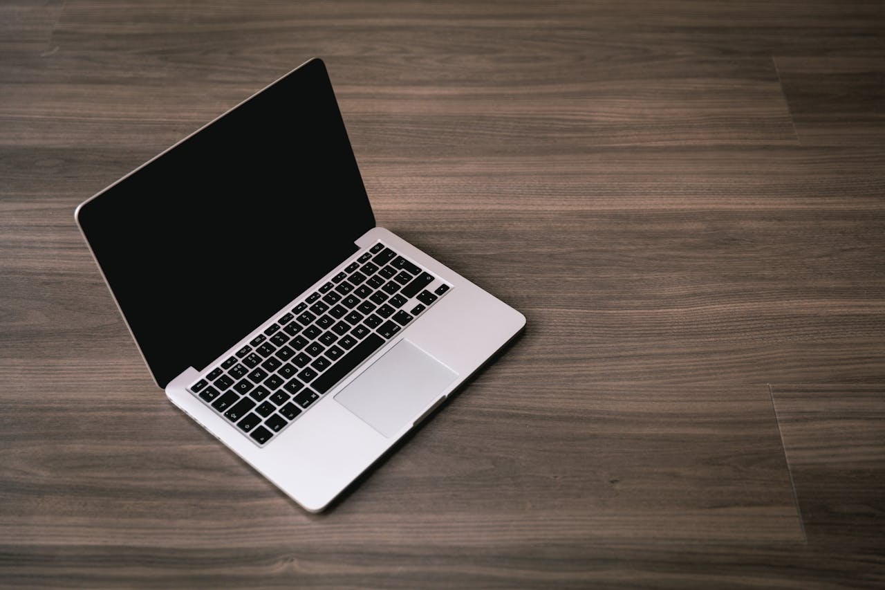 about-me-01 Sleek open laptop placed on a polished wooden floor, showcasing modern technology design.